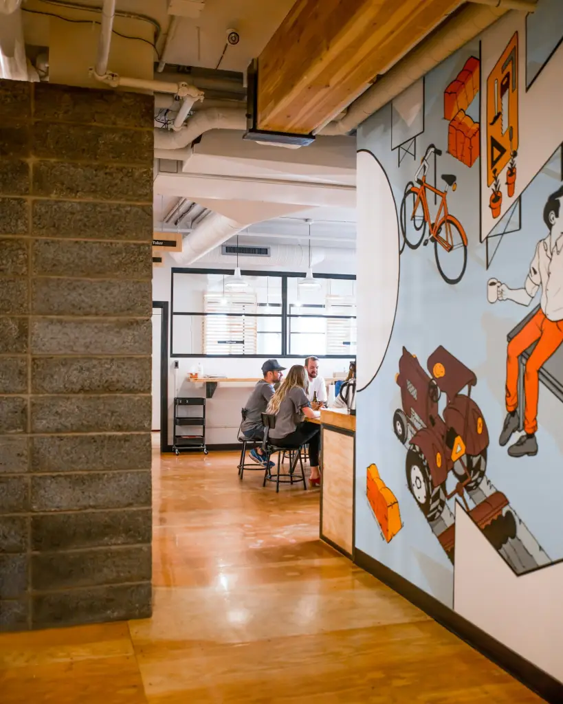 People collaborating in a modern office space with colorful wall art and wooden accents.