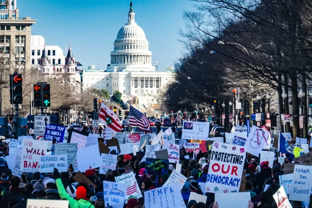 Peaceful protest with signs in front of the U.S. Capitol building advocating for democracy and rights.