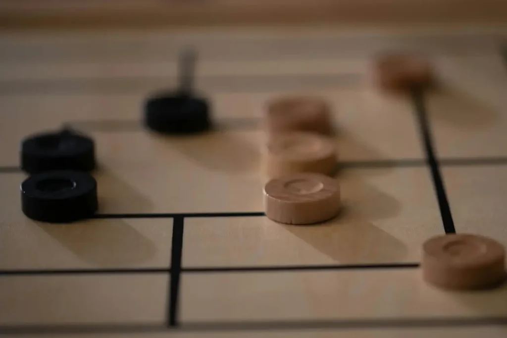 Wooden board game with black and brown pieces on a grid, close-up view showing strategic arrangement.