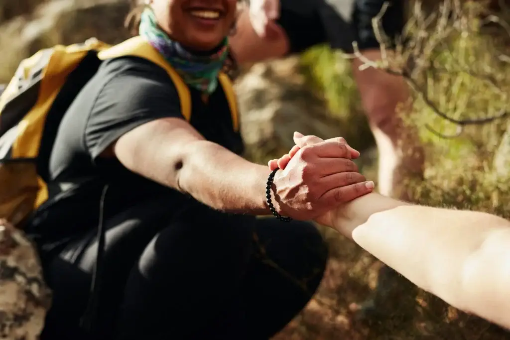 Hiker offering a helping hand on a trail, showcasing teamwork and support in nature's landscape.