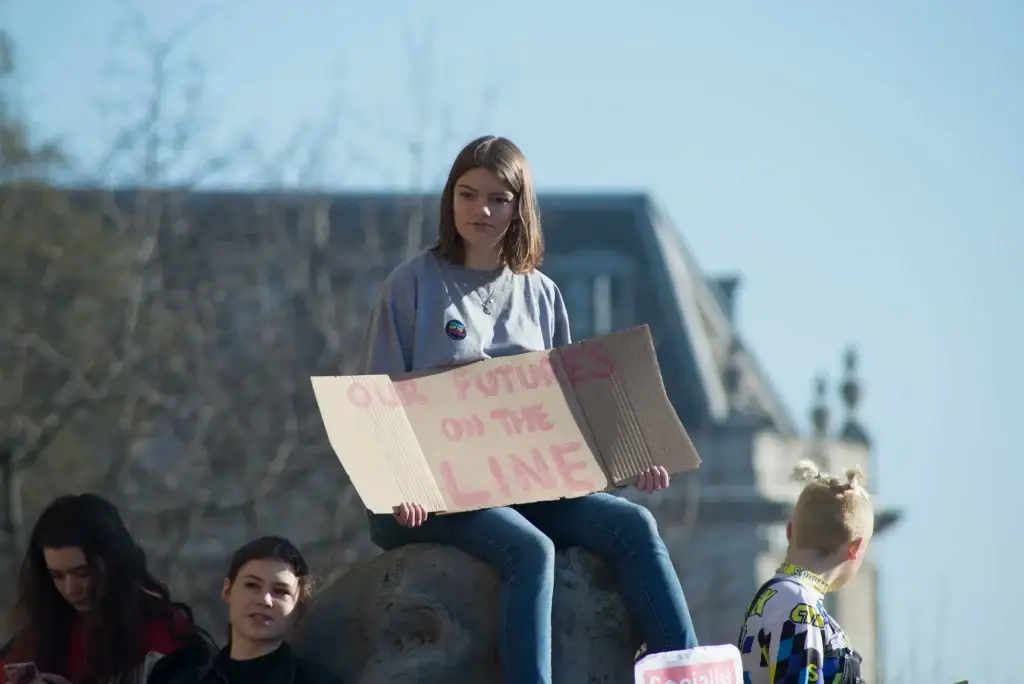 Young protester holding Our futures on the line sign, advocating for climate action at a rally.