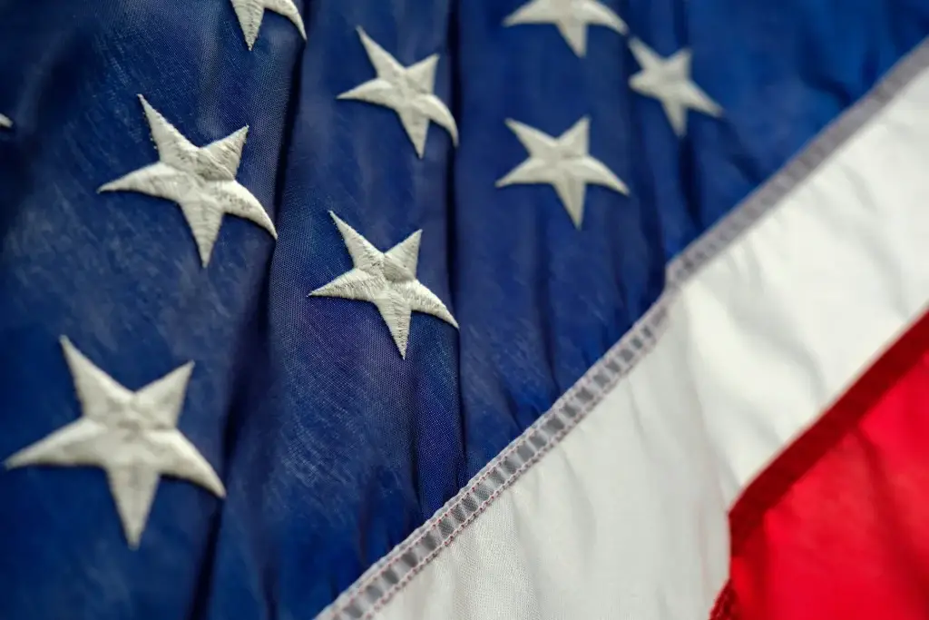 Close-up of American flag fabric with white stars on blue field, highlighting texture and colors.