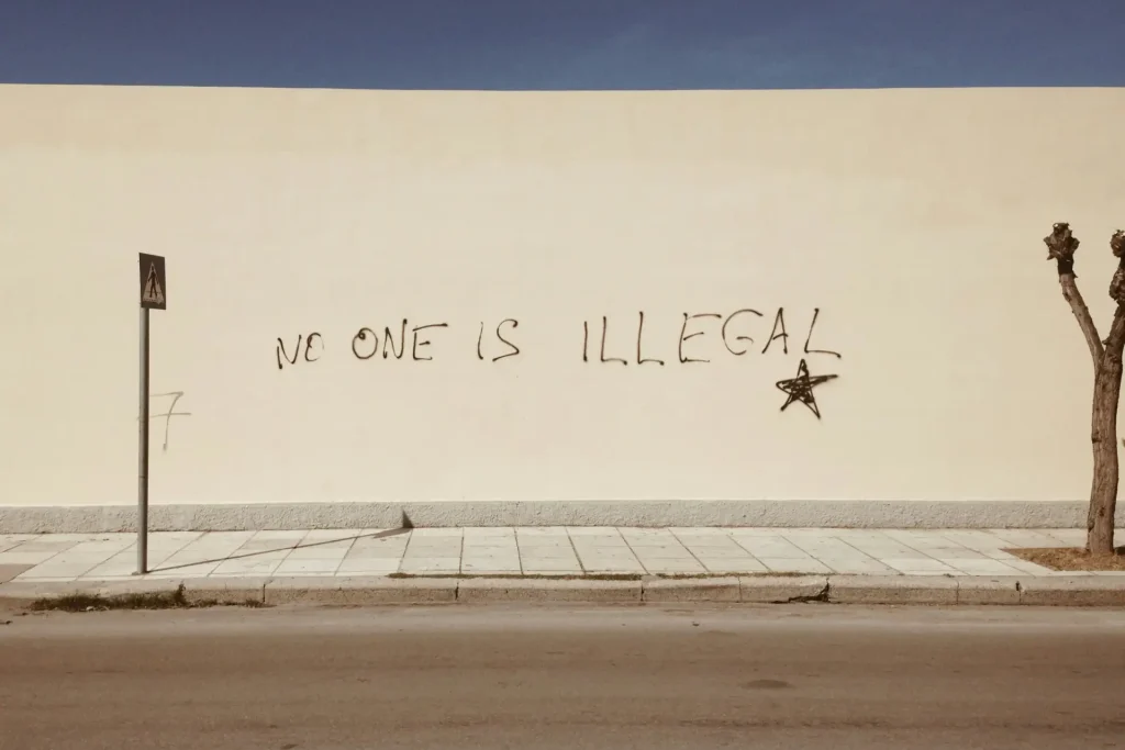 Graffiti on a wall reading No One Is Illegal with a star symbol, promoting social justice and equality.