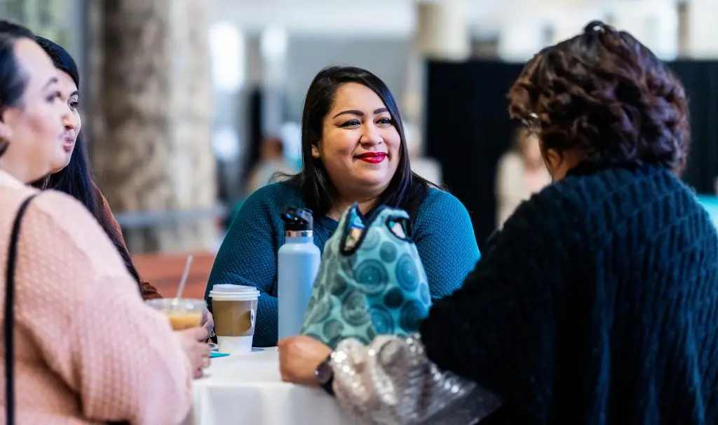 Women enjoying a conversation over coffee at a casual indoor gathering.