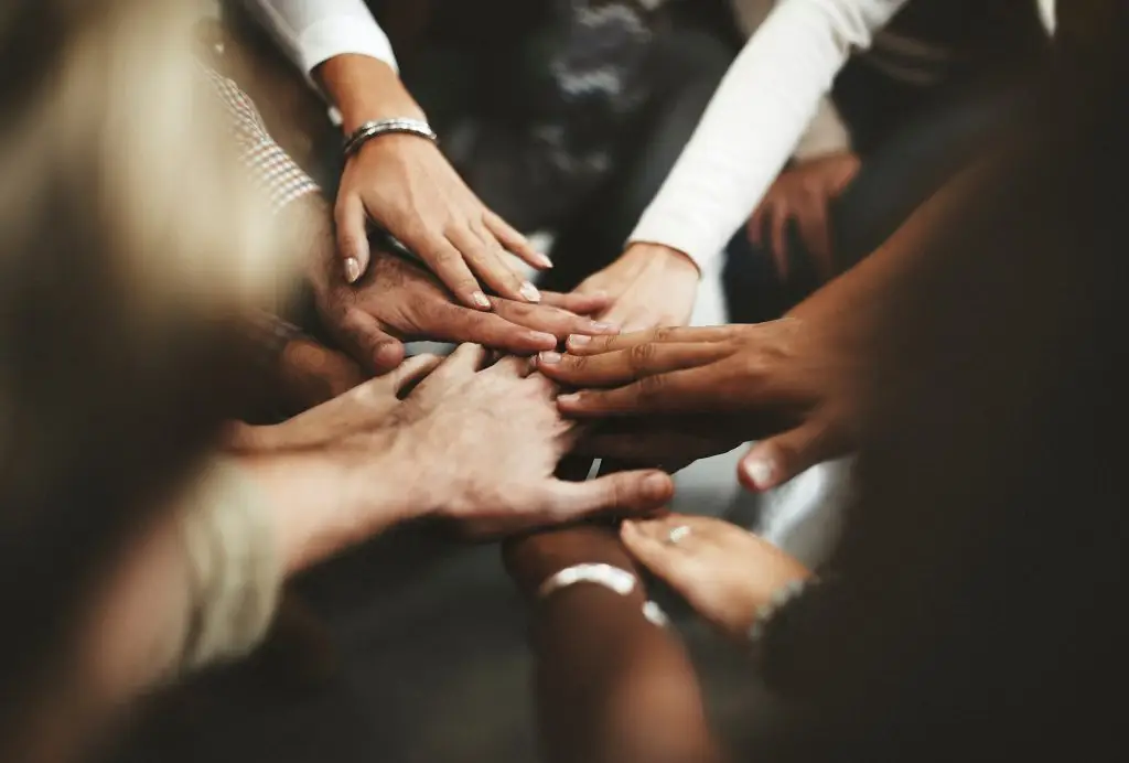 Diverse group of hands joined together, symbolizing unity and teamwork.