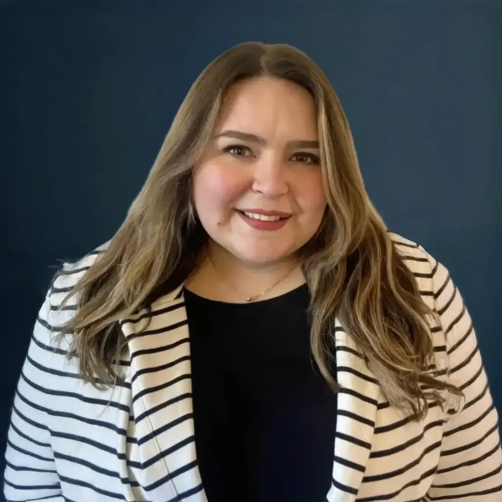 Smiling woman in striped blazer and black top against blue background.